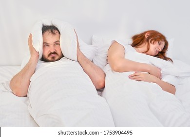 Der Mann bedeckte seinen Kopf mit einem Kissen, weil seine Frau schnarcht. Probleme beim Schlafen in der Familie. Relationship-Probleme verbunden mit Isolation durch Koronavirus.