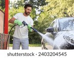 Man covering automobile with foam at outdoor car wash