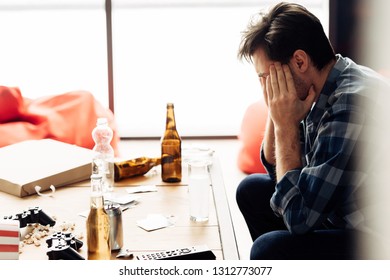 Man Covering Face And Suffering Hangover After Party