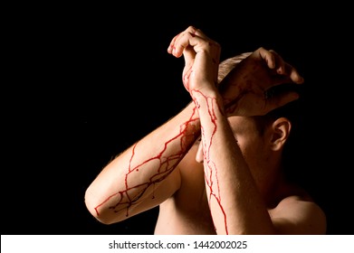 man covers his face with his hands on a black background, hands covered in blood