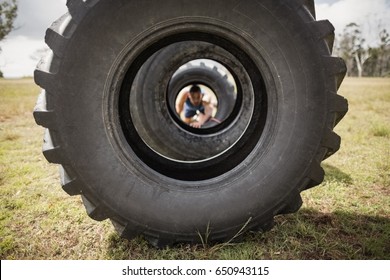 Man Crawling Through The Tire During Obstacle Course In Boot Camp