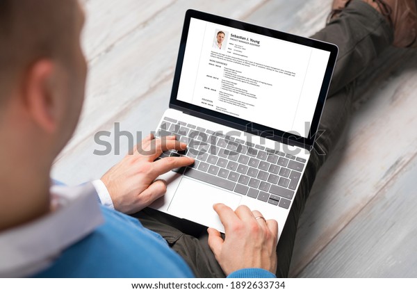 Man creating his CV on laptop. All contents in\
document are made up.