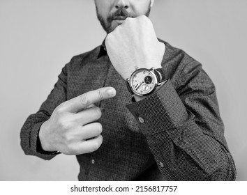 Man cropped view point finger at luxury wrist watch grey background, time