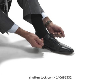 Man Crouches To Tie Dress Shoes