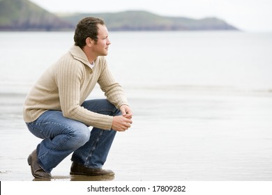 Man Crouching On Beach