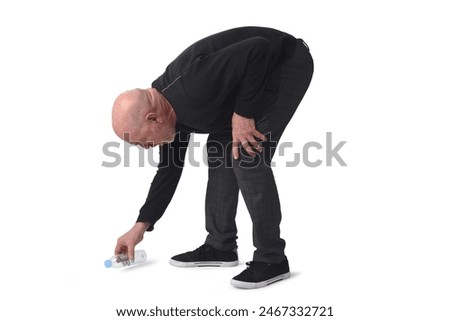 man crouching to pick up a plastic bottle from the ground on white background