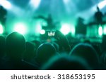 man in crowed with smart phone recording concert 