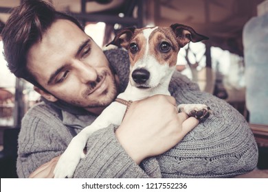 Man Cuddling With His Terrier Dog In Winter