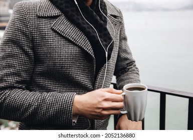 A man with a cup of coffee. A man drinks coffee 
next to the balcony against the view - Powered by Shutterstock