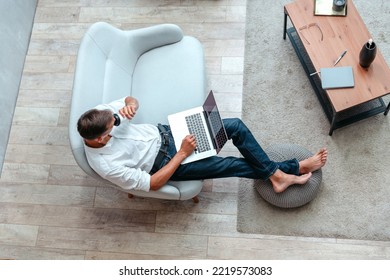 man with a Cup of coffee using a laptop while sitting on the sofa - Shutterstock ID 2219573083