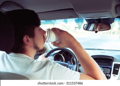 Man with a cup of coffee while driving. don't sleep and drive