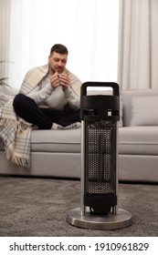 Man With Cup Of Hot Drink At Home, Focus On Electric Patio Heater