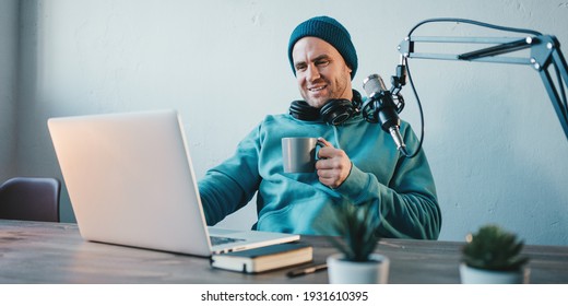 Man With Cup Streaming His Audio Podcast At Small And Cozy Home Broadcast Studio