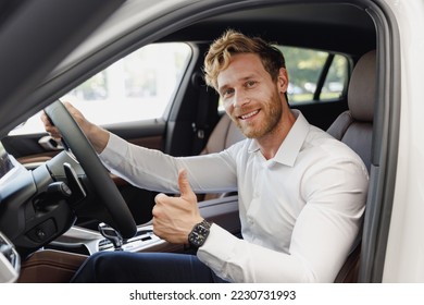 Man customer buyer businessman client wear classic suit sit in car salon show thumb up chooses auto wants to buy new automobile in showroom vehicle dealership store motor show indoor Car sales concept - Powered by Shutterstock