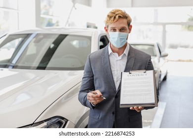 Man Customer Male Client Buyer 20s Wear Classic Grey Suit Pandemic Mask Choose Auto Want Buy New Car Automobile Hold Sign Documents In Showroom Salon Dealership Store Motor Show Indoor Sale Concept.