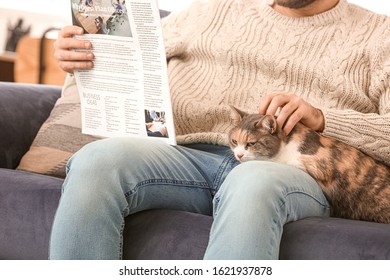 Man With Cute Cat Reading Newspaper At Home