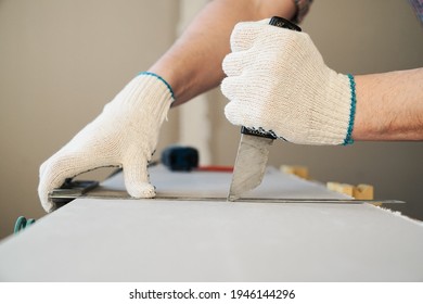 A man cuts a drywall sheet with a knife