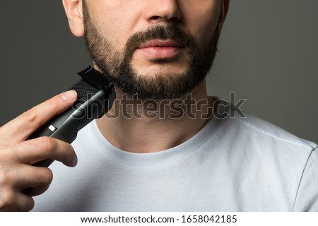 Man cuts his beard with a trimmer