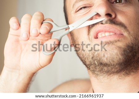 man cuts his hair in nose