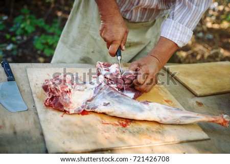 The man cuts meat of a ram for pilaf.