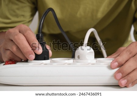 A man cuts off the electric current at a white electrical socket to reduce energy consumption