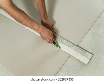 Man cuts off a piece of drywall with a knife and a ruler - Shutterstock ID 282987335