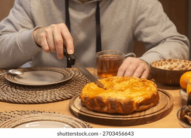 A man cuts a piece of pie while sitting at the dining table. Home food. Tea time