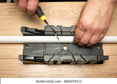 A Man Cuts A Polystyrene Baseboard With A Clerical Knife Using A Box To Cut Corners. Renovation Work. Repair In The Apartment. Expanded Polystyrene Panel.