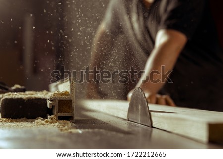 A man cuts wood on a circular saw in a joinery