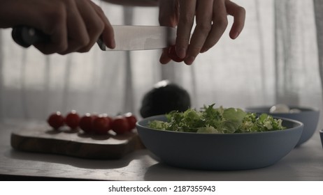 Man Cutting Cherry Tomatoes Into Salad With Window Backlight, Wide Photo