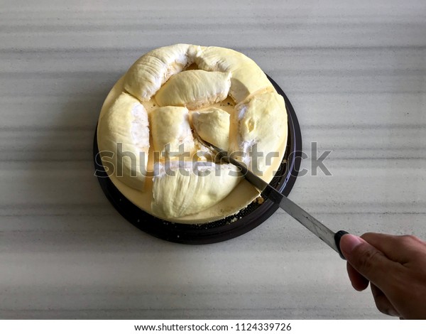 Man cutting durian cake by knife,\
creative bakery in Thailand, snack from tropical fruit\
