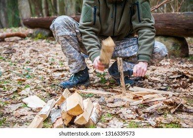man cutting a firewood stick for campfire with knife - Shutterstock ID 1316339573