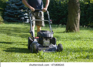 Man cutting grass by lawn mower, powerful petrol lawn mower in sunlight  - Shutterstock ID 471808265