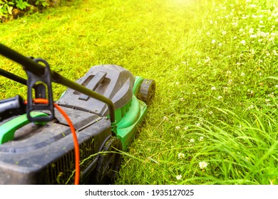 Man Cutting Green Grass With Lawn Mower In Backyard. Gardening Country Lifestyle Background. Beautiful View On Fresh Green Grass Lawn In Sunlight, Garden Landscape In Spring Or Summer Season