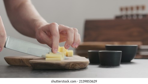 man cutting hard cheese with knife on wood board
