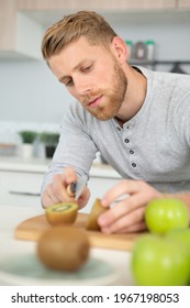 Man Cutting A Kiwi Fruit In Half