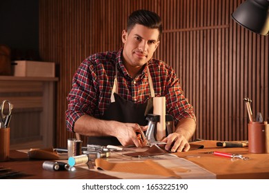 Man Cutting Leather With Scissors In Workshop