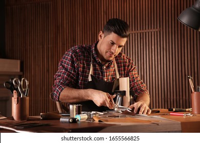 Man Cutting Leather With Scissors In Workshop