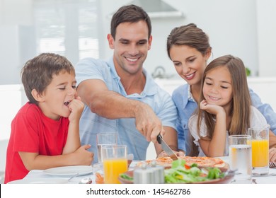 Man Cutting A Pizza For His Family For The Dinner