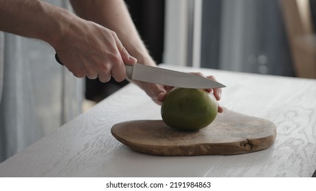 Man Cutting Ripe Mango On Olive Board On White Oak Table