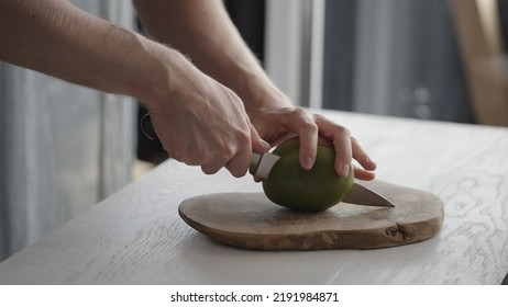 Man Cutting Ripe Mango On Olive Board On White Oak Table