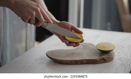 Man Cutting Ripe Mango On Olive Board On White Oak Table