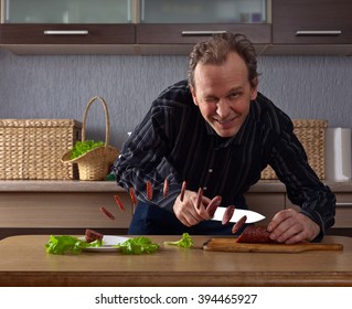 Man Cutting Slices Of Sausage On The Kitchen Table