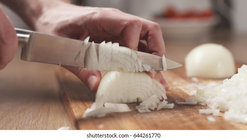 man cutting white onion with knife, wide photo