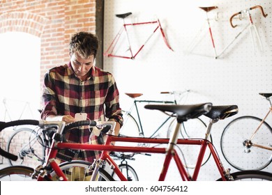 A Man In A Cycle Shop, Reading The Price Label On A Bike