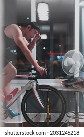 Man Cycling On The Machine Trainer He Is Exercising In The Home At Night Playing Online Bike Racing Game