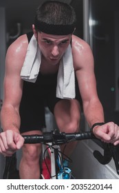 Man Cycling On The Machine Trainer He Is Exercising In The Home At Night Playing Online Bike Racing Game