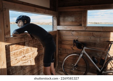 A man cyclist  and his gravel bike ready to explore nature.Birdwatching on wheels: cyclist in an observation hut. Cycling adventure.Elche, Alicante, Spain - Shutterstock ID 2269581327