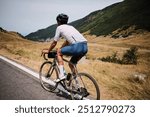 Man cyclist is riding bicycle on Transfagarasan road. A cyclist is practicing cycling. Sport motivation. Adventure travel on bike.Cycling in Carpathian Mountains. Transfăgărășan, Romania.