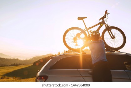 Man Cyclist Veared In Cycling Clothes And Protective Helmet Instals His Mountain Bike On The Car Roof